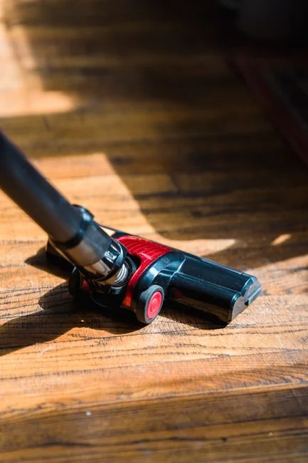 A professional cleaner in protective gear vacuuming the floor in a modern living room.